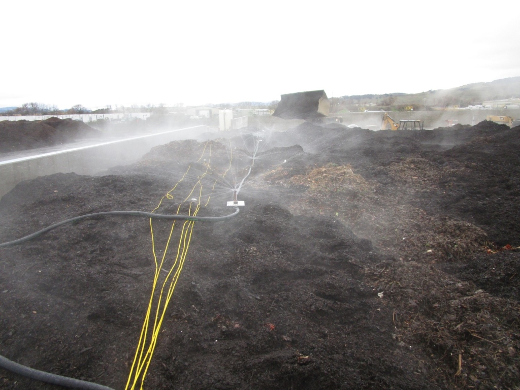 Sprinkler system applying water to a compost pile