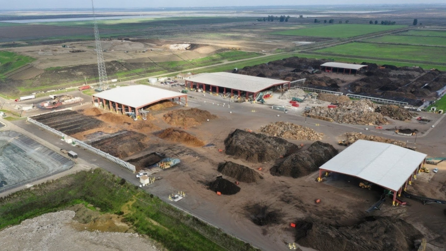 compost site with processing buildings and piles in background