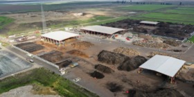 compost site with processing buildings and piles in background